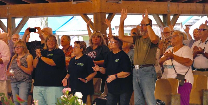 Camp meeting attendees get on their feet as the music inspires them.